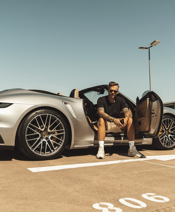 Sven Knobloch sitzt in einem Porsche auf einem Parkplatz