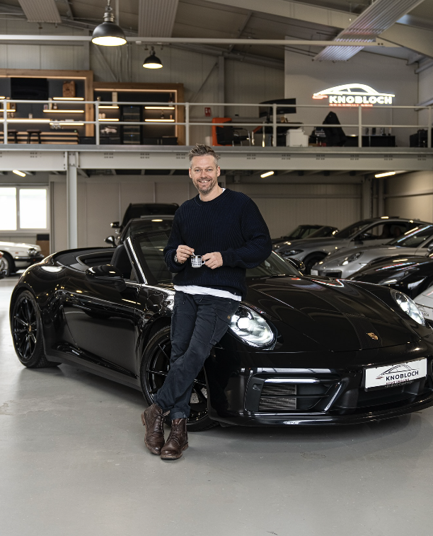 Sven Knobloch lehnt an einem schwarzen Porsche Cabrio